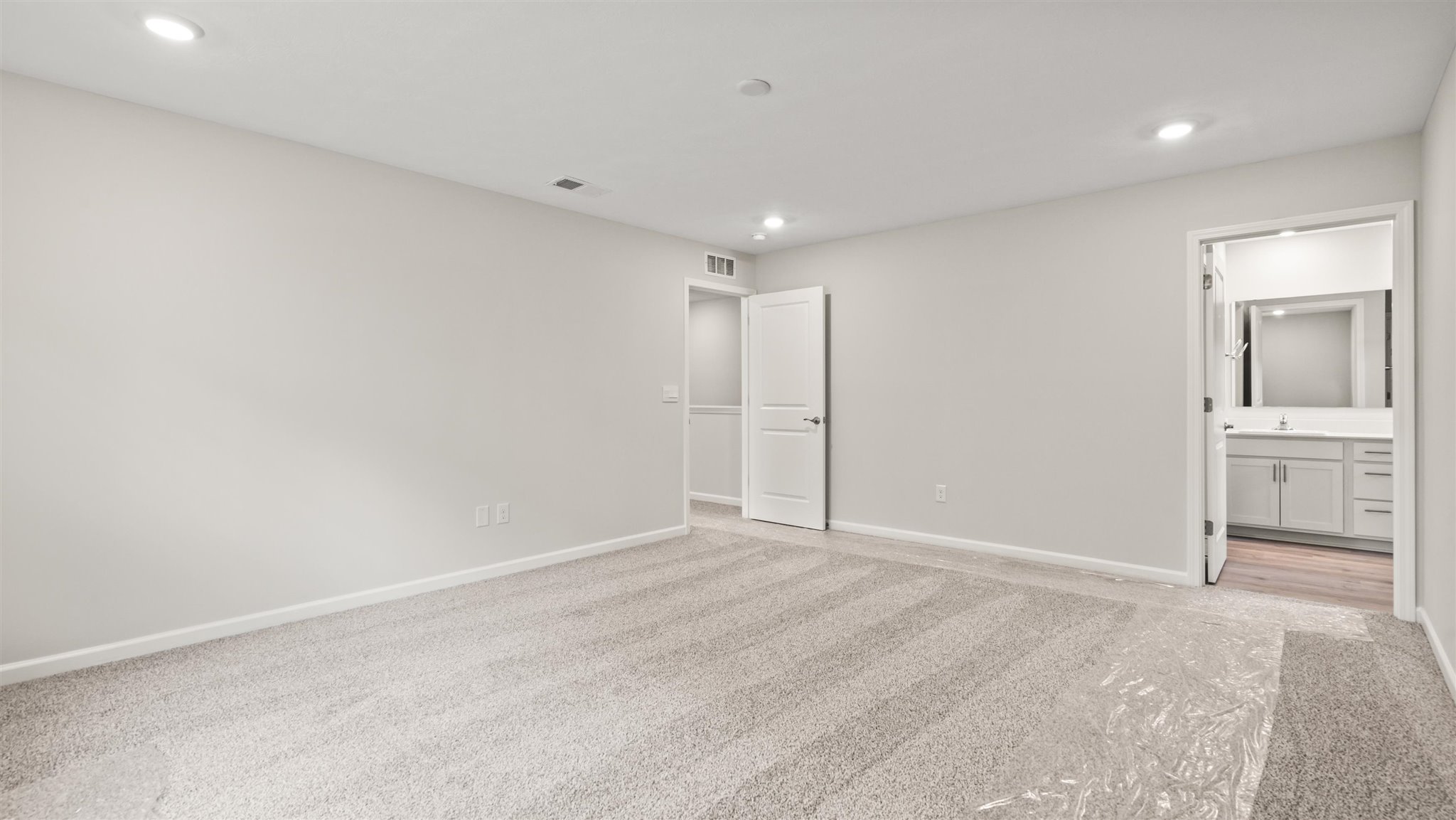 Primary bedroom with carpet and doorway to ensuite bath.