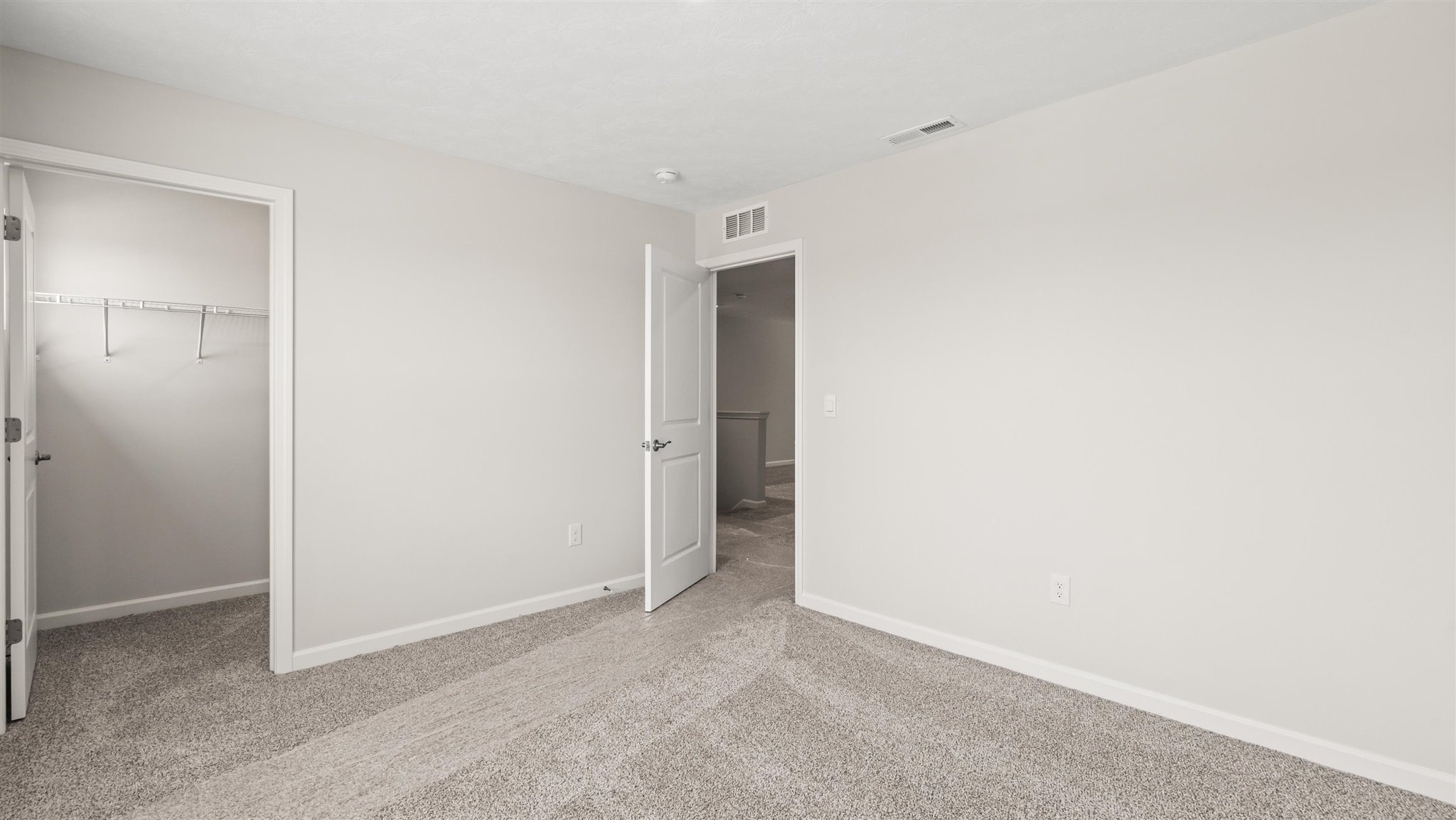 Bedroom with carpet, closet, and entrance to hallway