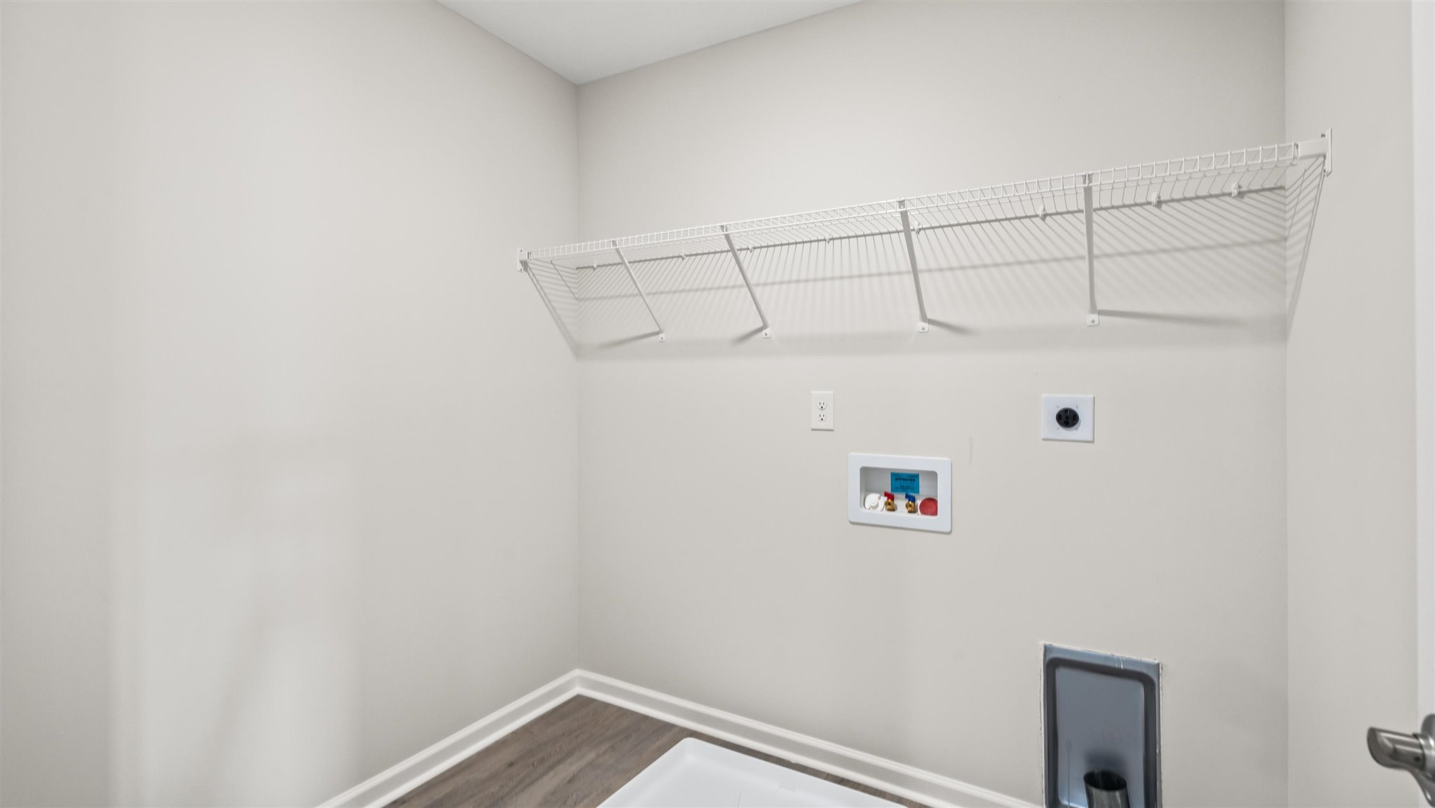 Laundry area with shelving and washer/dryer inlets.