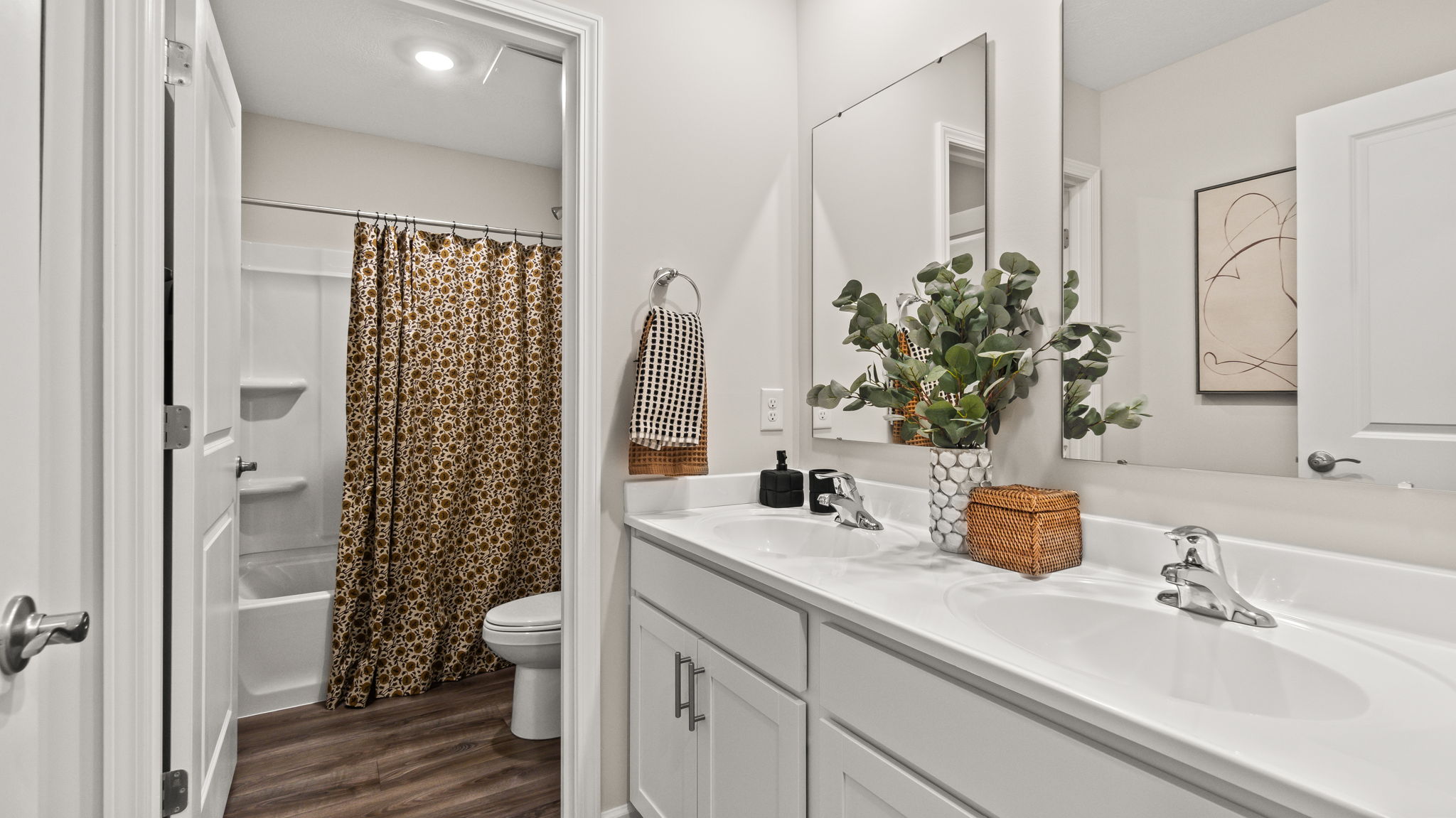 Closeup of bathroom, dual-vanity sink, and door to toilet and shower.
