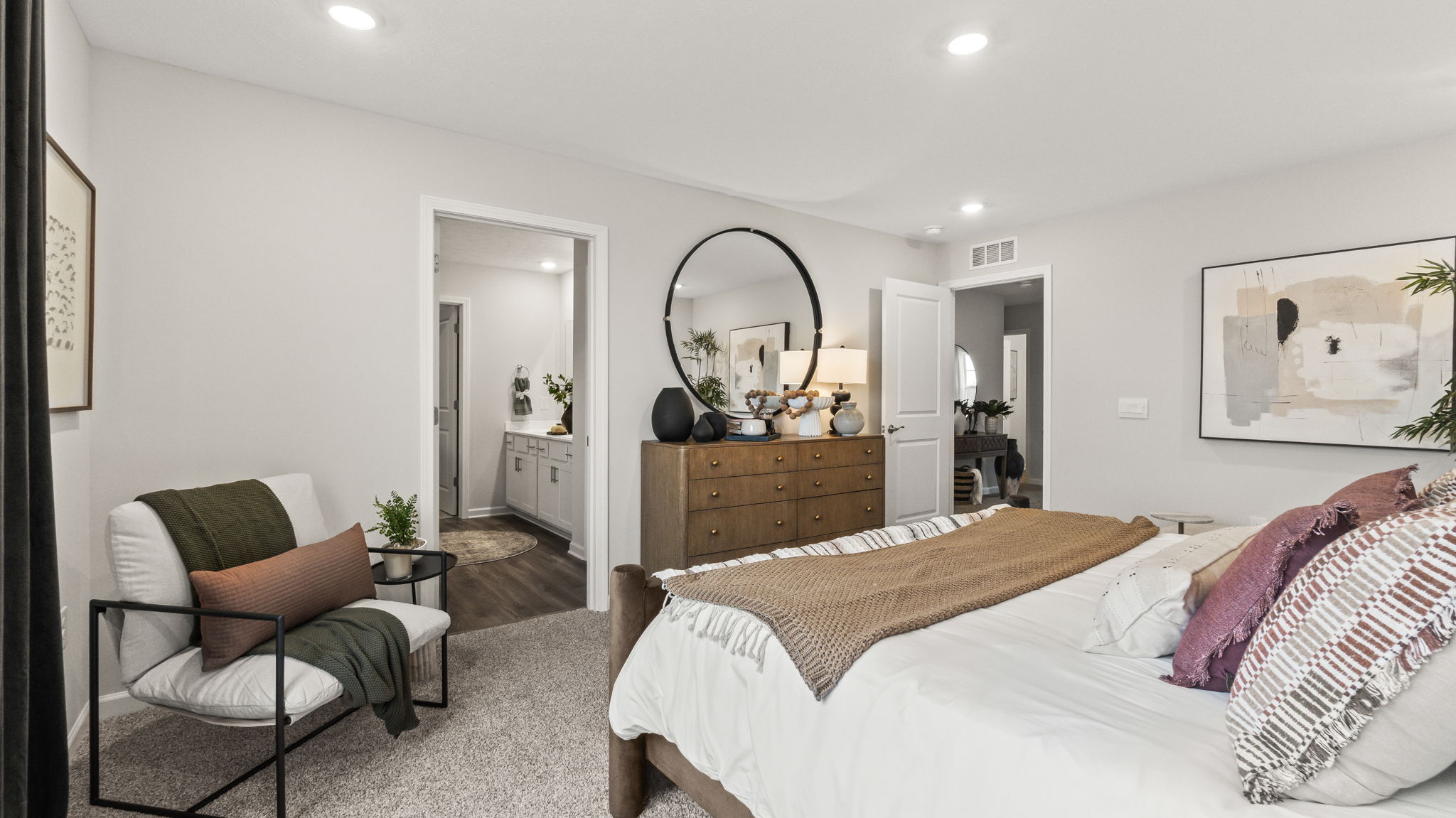 Primary bed and chair leading into bathroom.