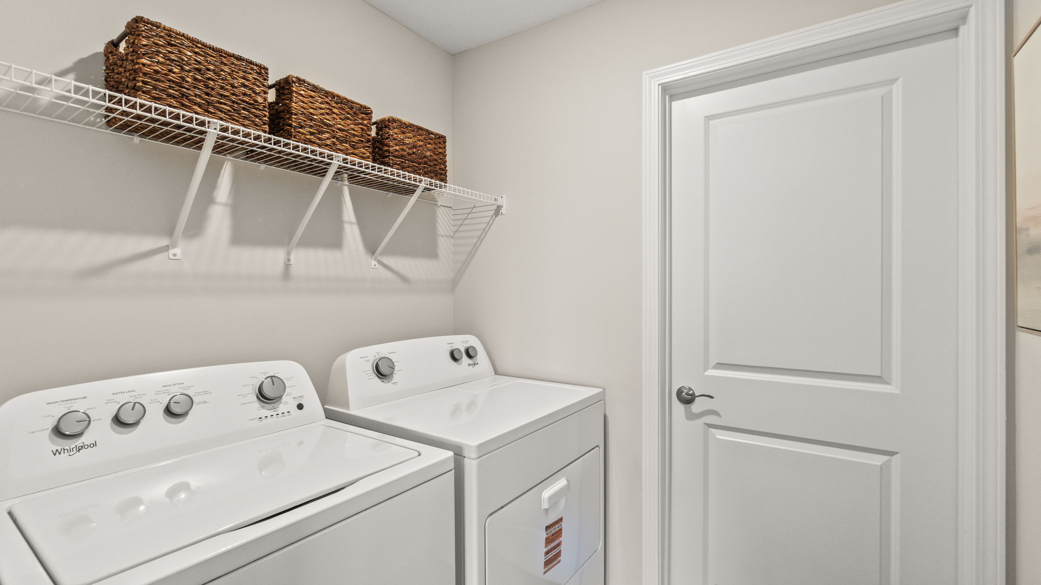 Laundry room with washer, dryer, and storage shelving .