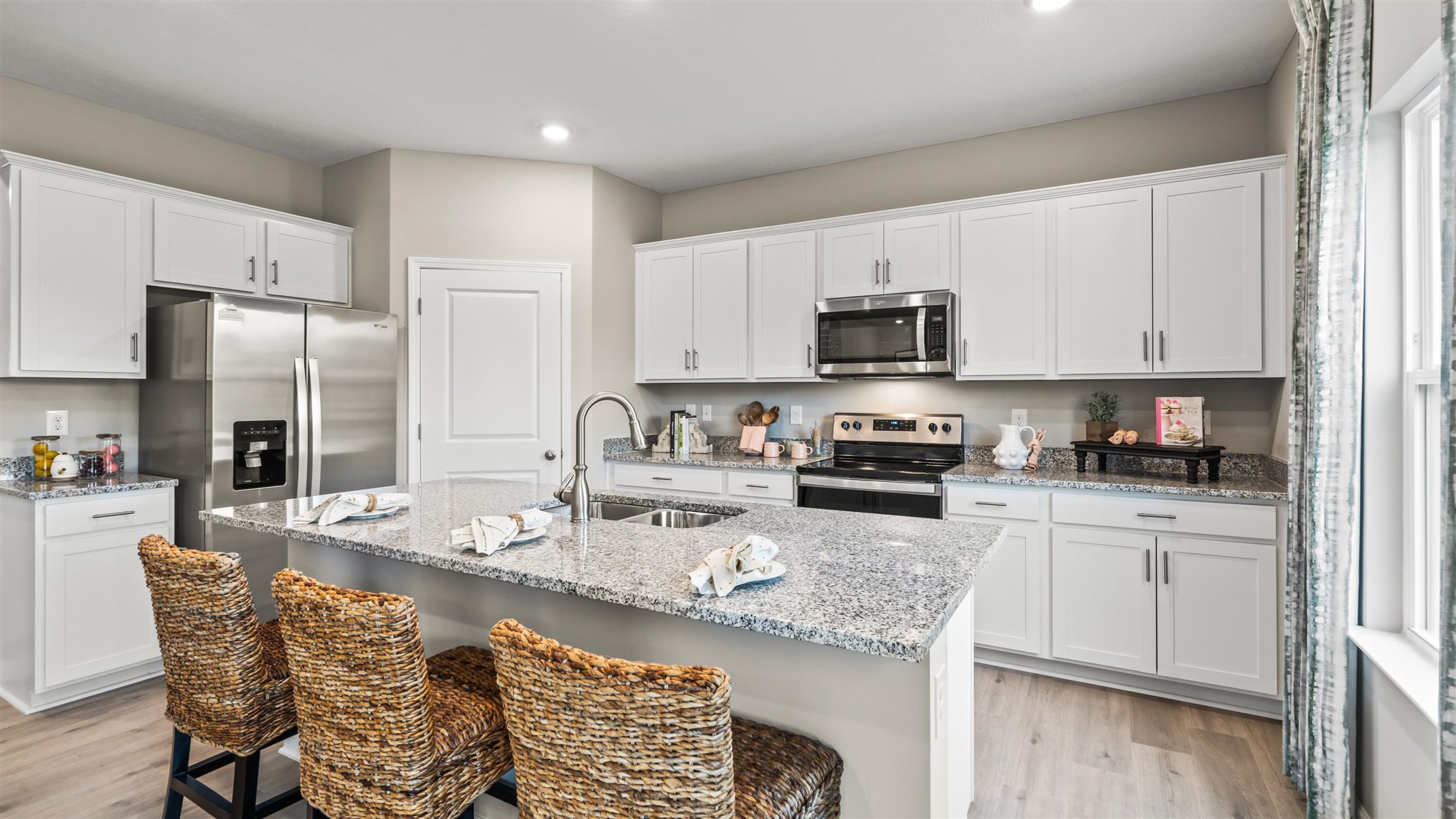 Right side view of kitchen with large kitchen island and stainless steel appliances.