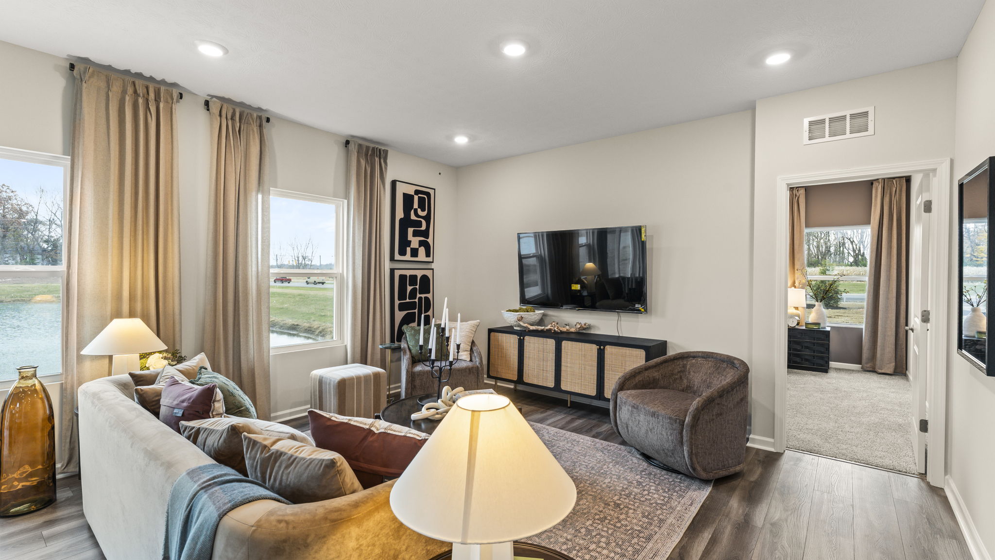 Full living room with modern art, brown furniture, and door to bedroom.