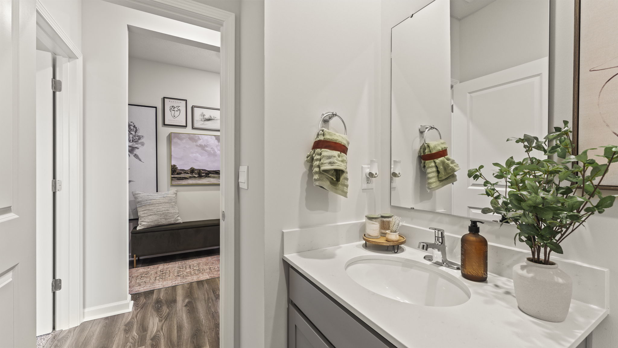 Bathroom with sink and mirror that also has a view of the hallway art.