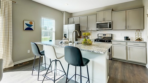 kitchen island with barstools, grey cabinets and appliances