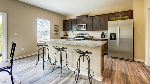 kitchen island with barstools, brown cabinets and appliances