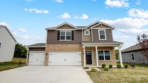 two story home with brown siding, partial stone front, covered front porch, three car garage