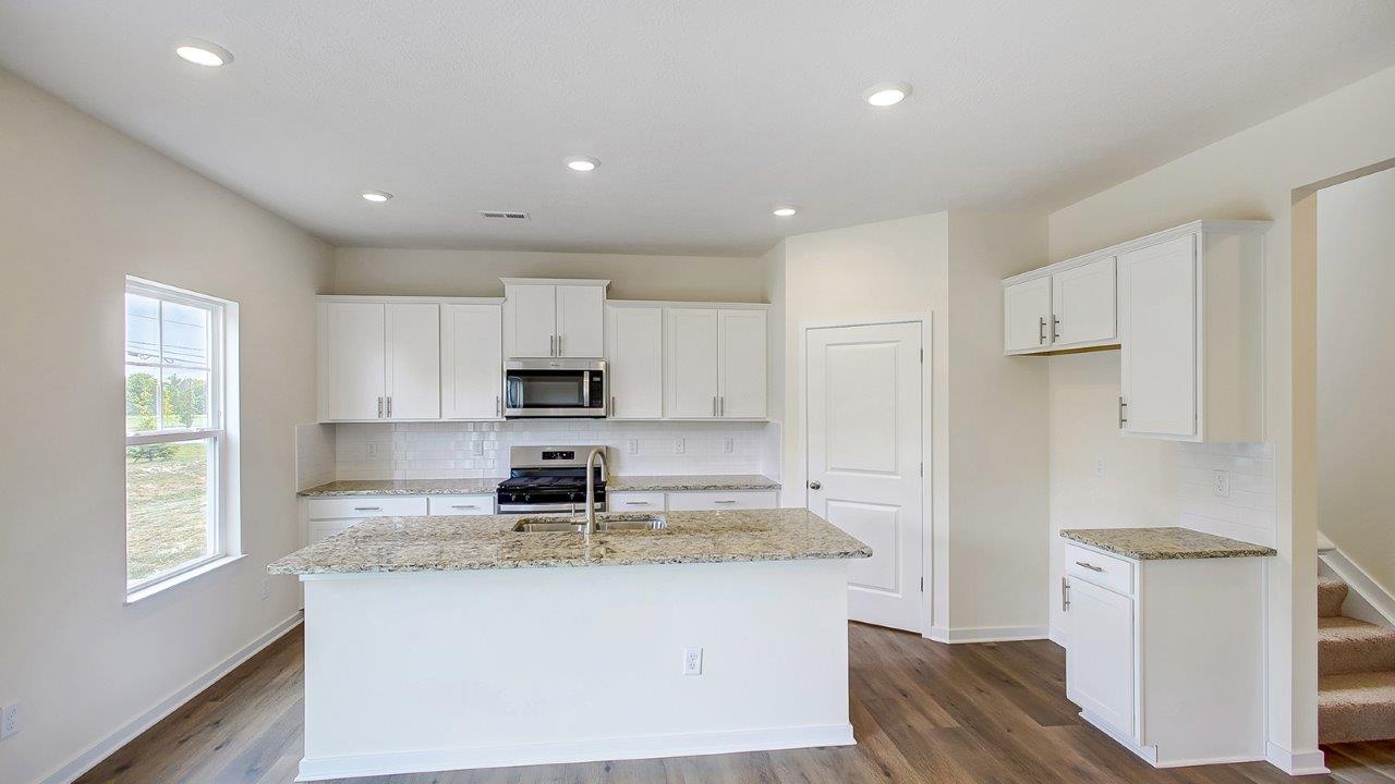 kitchen with white cabinets, built in island, single window and walk in pantry