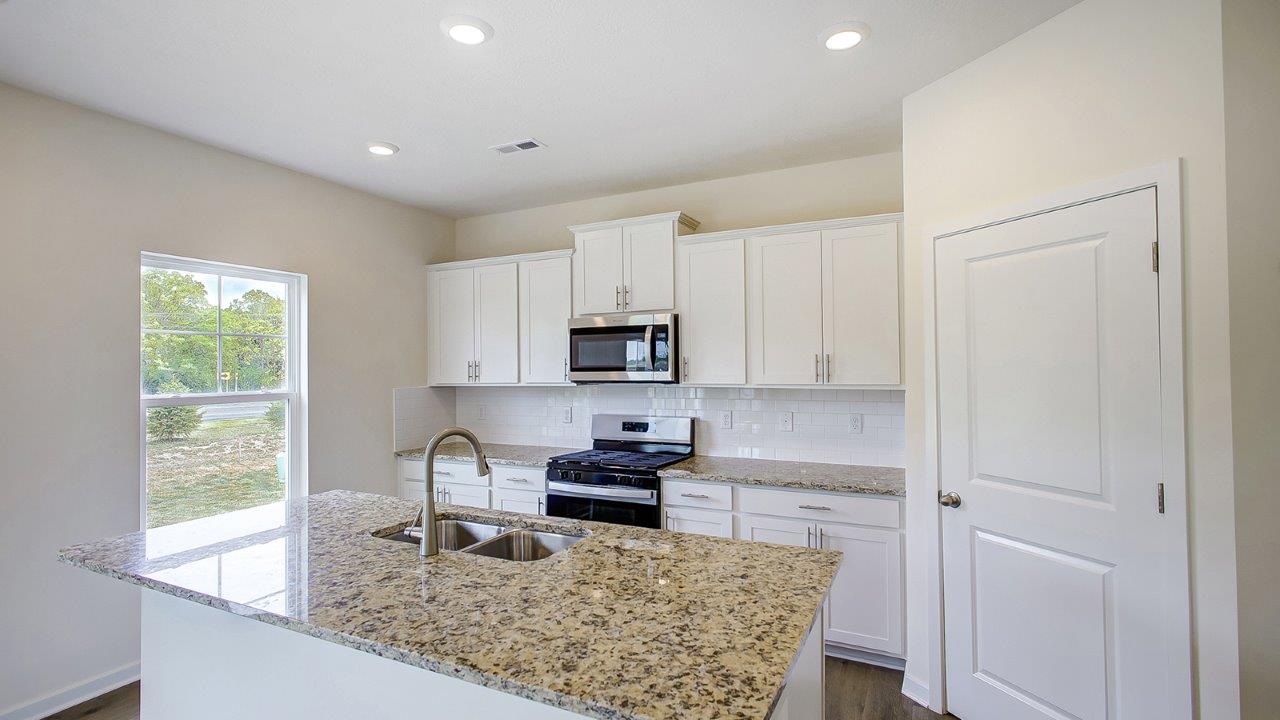 kitchen with white cabinets, built in island, single window and walk in pantry