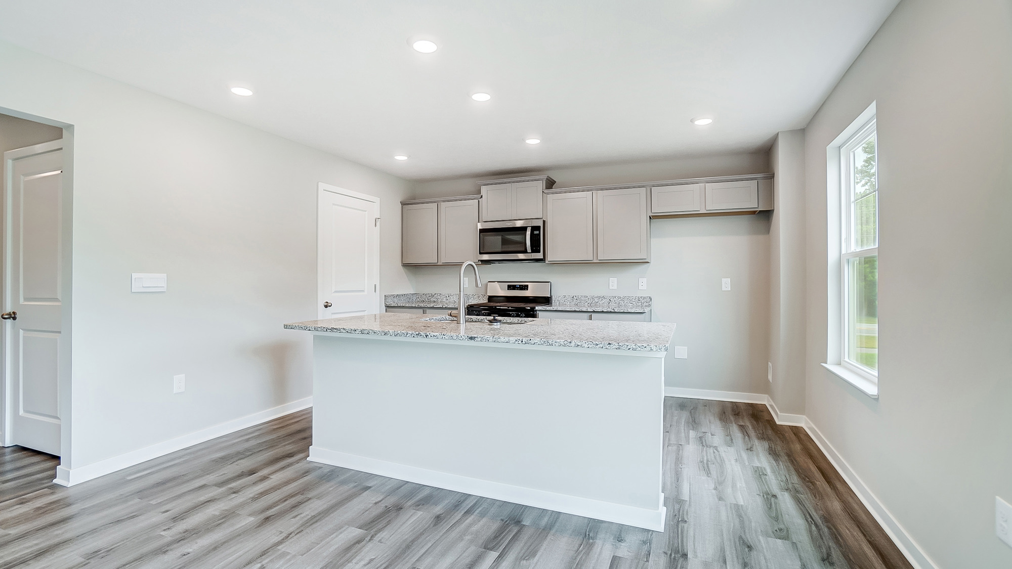 kitchen with grey cabinets, built in island, stainless steel appliances, walk in pantry