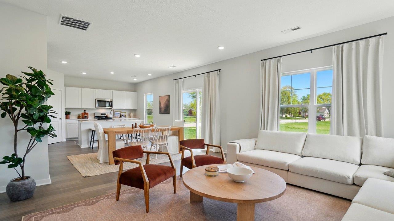 Living room featuring a white sectional against 2 windows, an orange rug and 2 red accent chairs