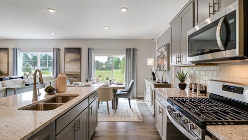 kitchen with grey cabinets, stainless steel appliances, built in island and dining space