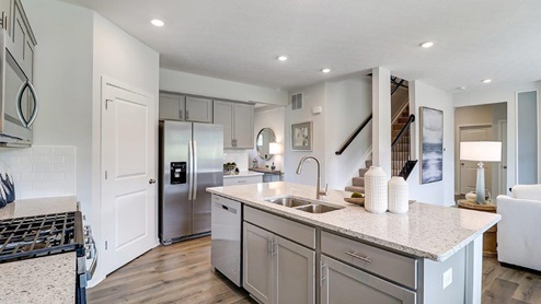 kitchen with grey cabinets, stainless steel appliances, built in island with barstools, corner walk in pantry