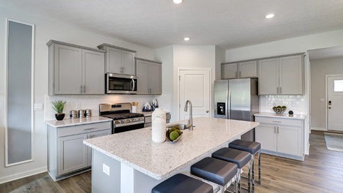 kitchen with grey cabinets, stainless steel appliances, built in island with barstools, corner walk in pantry