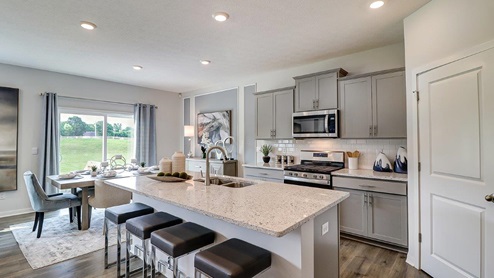 kitchen with grey cabinets, stainless steel appliances, built in island with barstools, corner walk in pantry