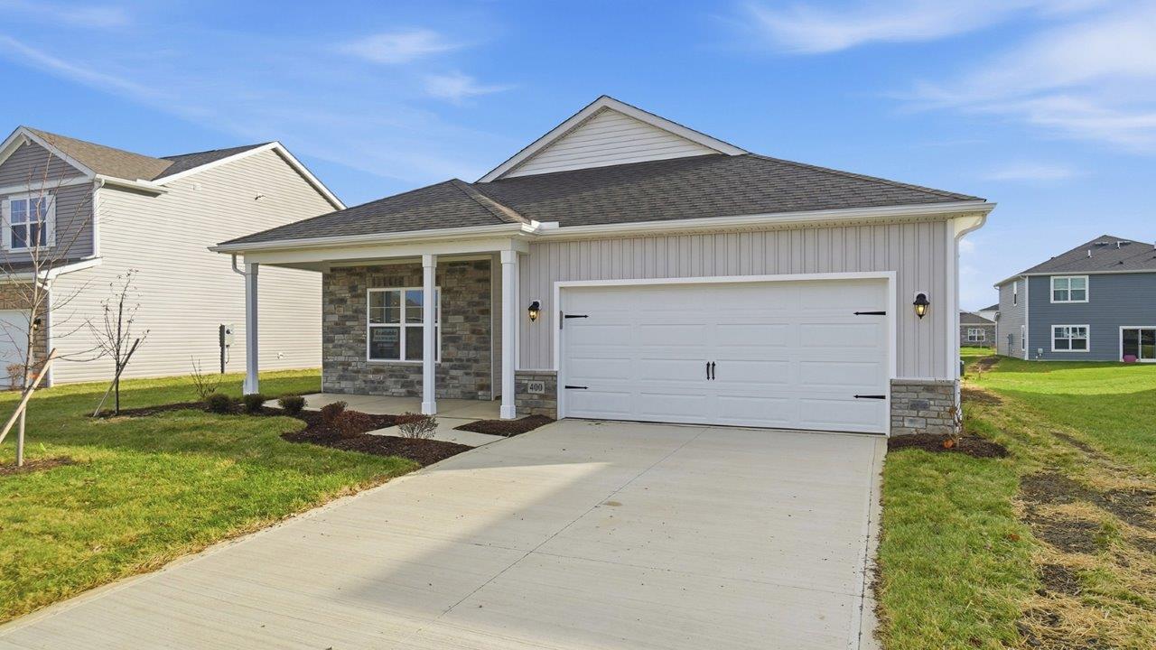 single story home with grey siding, stone front, covered front porch and two car garage
