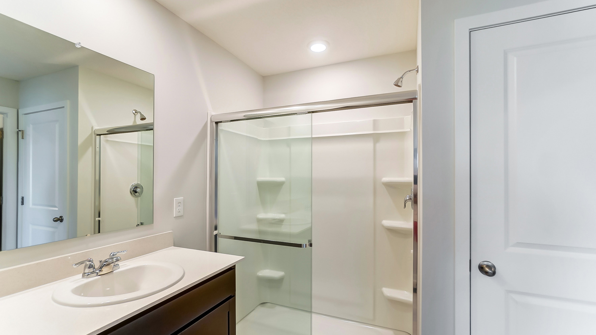 bathroom with dual vanity sinks, and a walk in shower