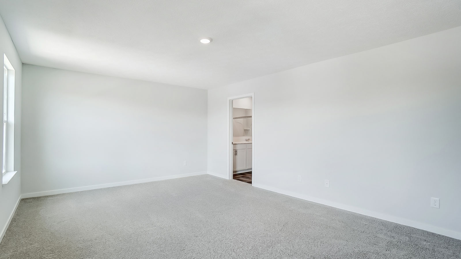 Primary bedroom with large windows and neutral walls.