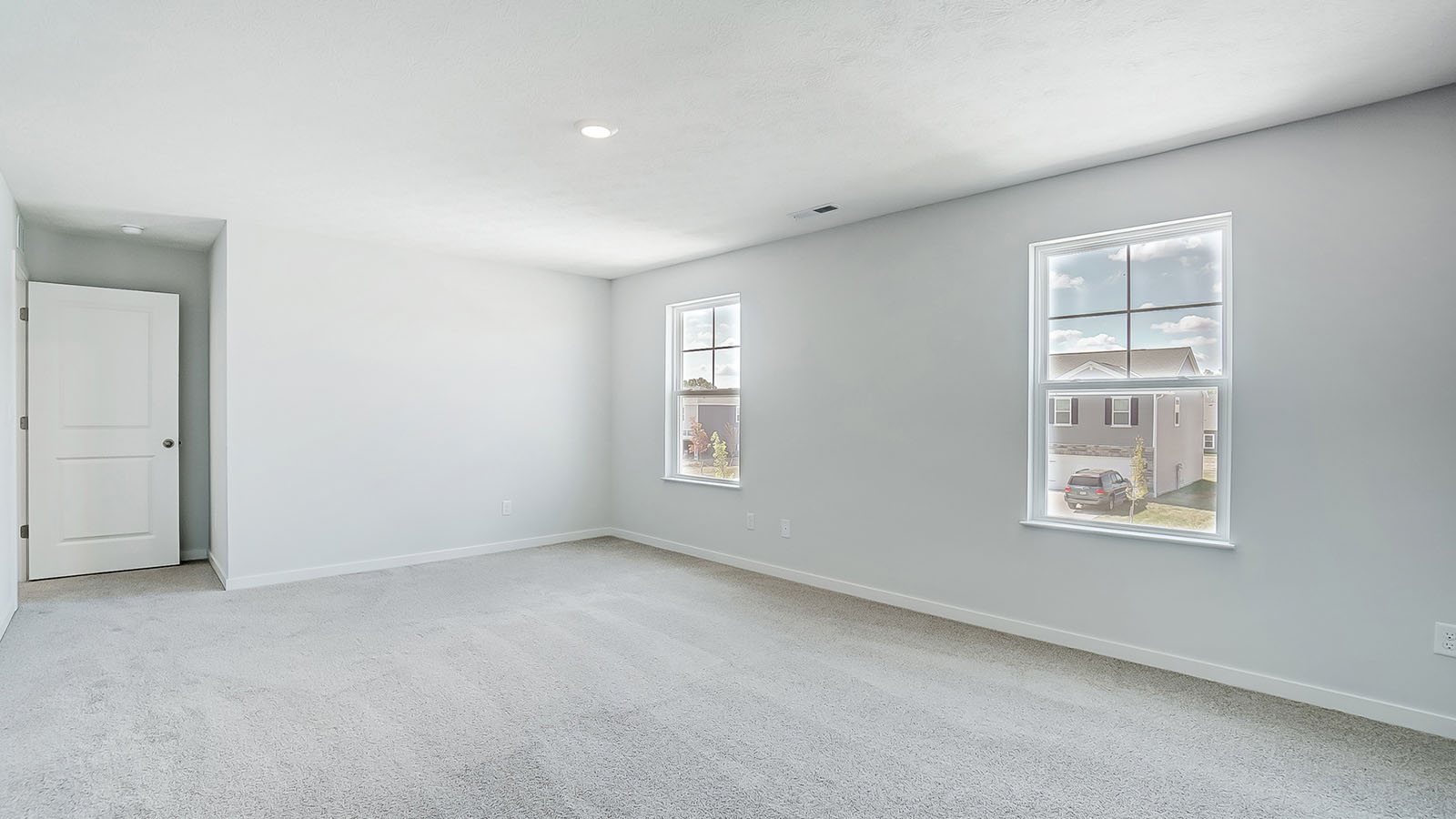 Primary bedroom with carpet, natural lighting, and a bathroom attached.