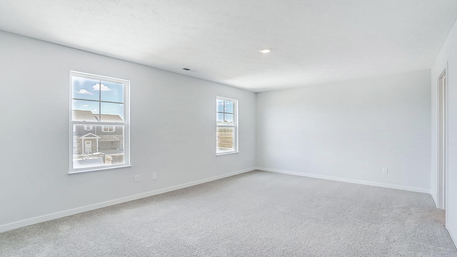 Primary bedroom with large windows and neutral walls.