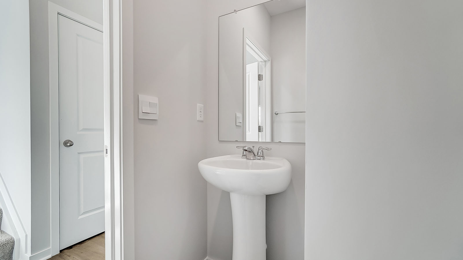Half bath with standing sink and long mirror above.
