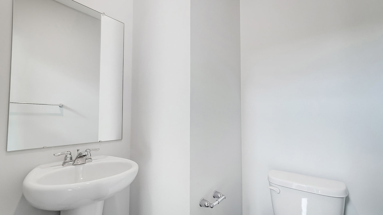 Half bath with standing sink and long mirror above.