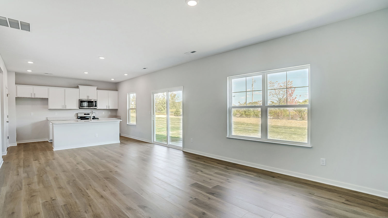 Main living area with clean flooring and natural light connecting to kitchen.