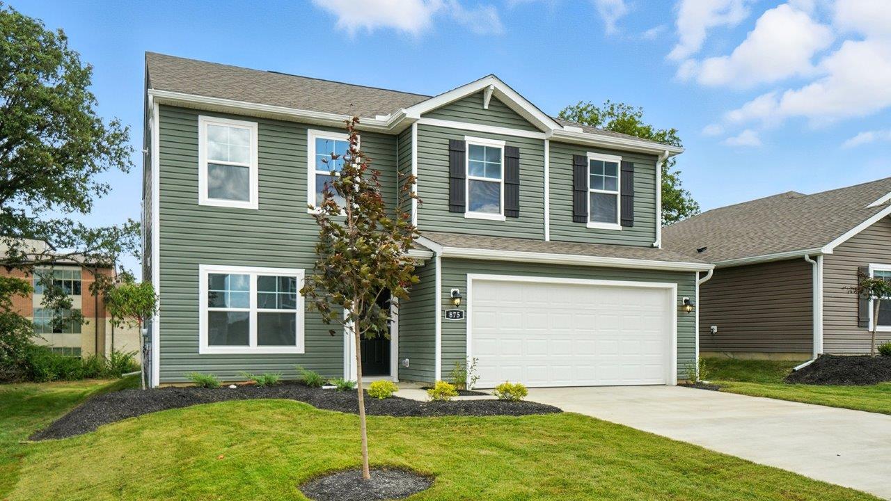 two story home with green siding, covered entry and two car garage