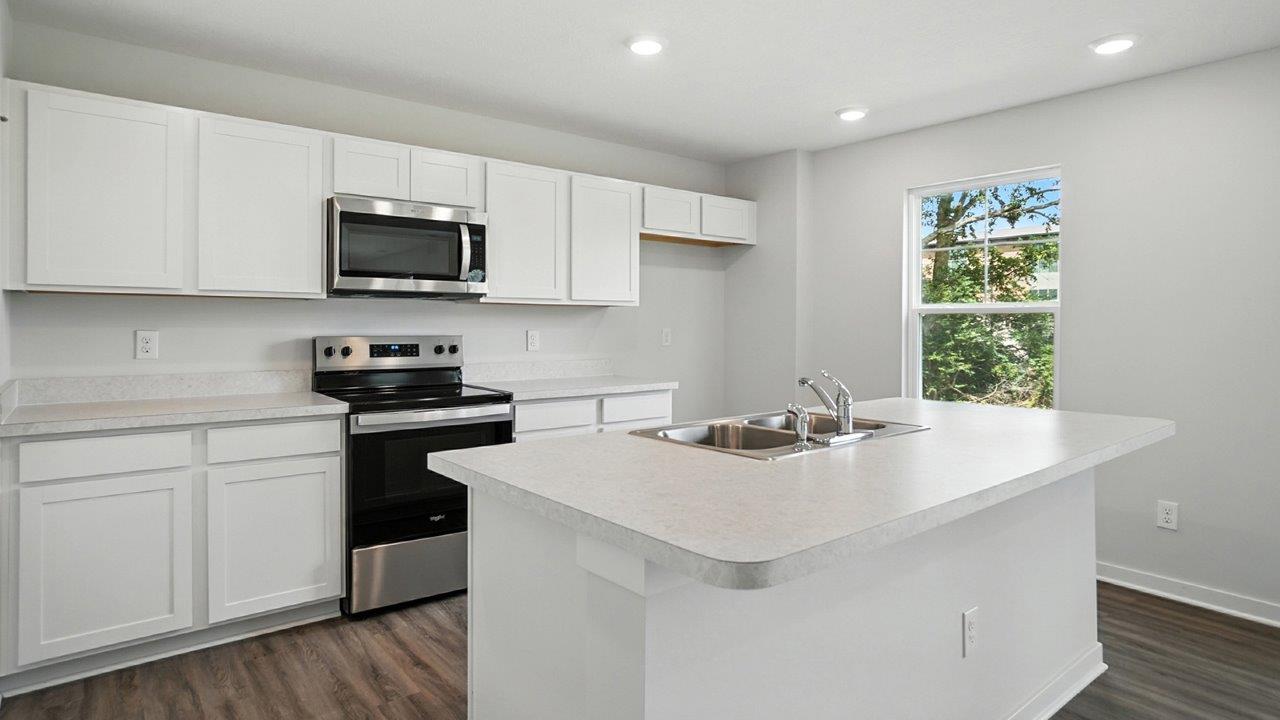 kitchen with white cabinets, built in island, stainless steel appliances and single window