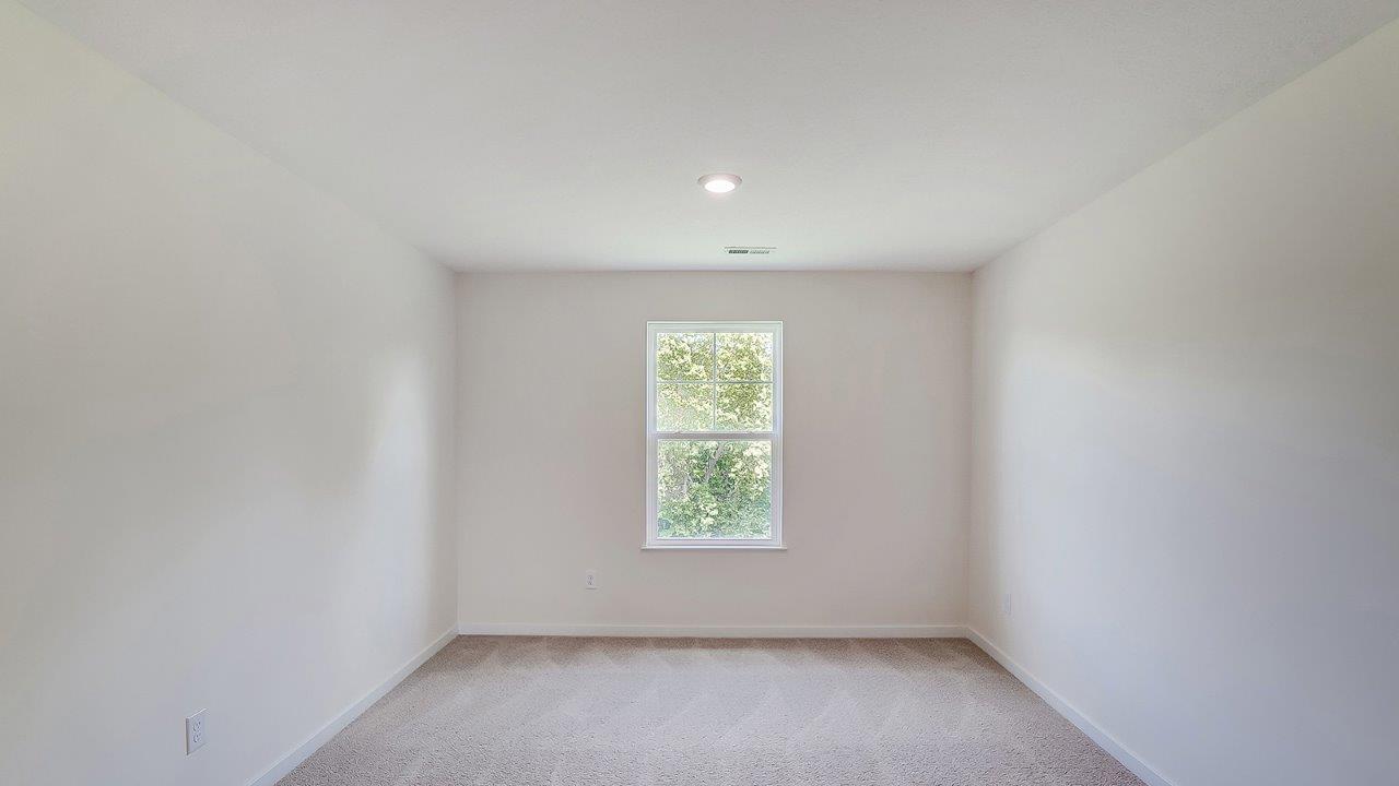 Secondary Bedroom in this New Home by D.R. Horton includes soft carpet, large window, and neutral paint ideal for guest or child use