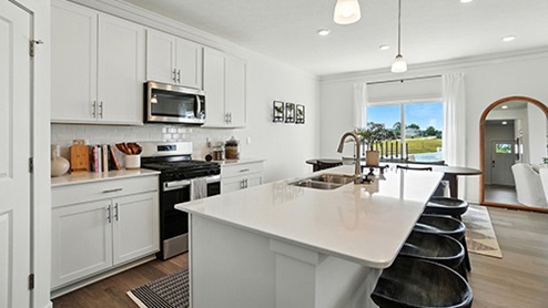 Kitchen Island View with Black barstools, white cabinets and stainless steel appliances