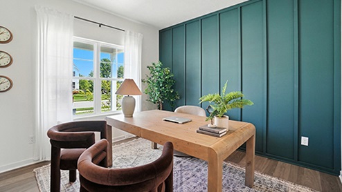 Office space with light wood desk, brown velvet arm chairs with teal wall with wood detail