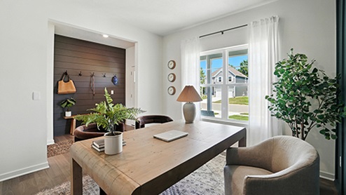 Office space with light wood desk, brown velvet arm chairs with teal wall with wood detail
