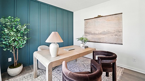 Office space with light wood desk, brown velvet arm chairs with teal wall with wood detail