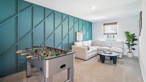 Loft space with cream sofa, dark coffee table, foosball table with teal wall with wood detail