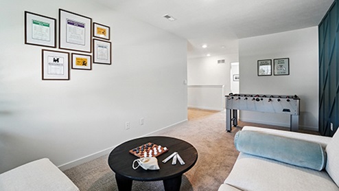 Loft space with cream sofa, dark coffee table, foosball table with teal wall with wood detail
