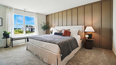 Primary bedroom with neutral bedding and brown wall with wood detail