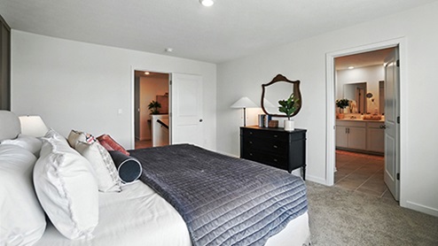 Primary bedroom with neutral bedding and brown wall with wood detail
