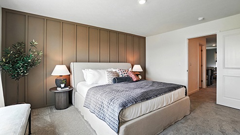Primary bedroom with neutral bedding and brown wall with wood detail