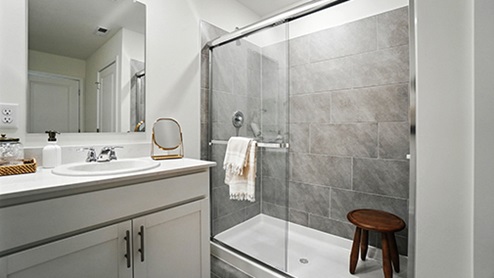 Primary bathroom with light gray cabinets featuring double sinks and mirrors