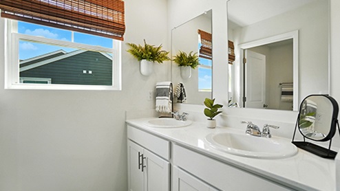 Bathroom with light gray cabinets featuring dual sinks and mirrors