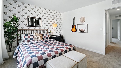 Boy’s bedroom decorated with checkered bedding and western themed wallpaper