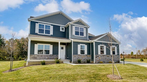 two story home with blue siding, stone water table, covered front porch and sideload garage