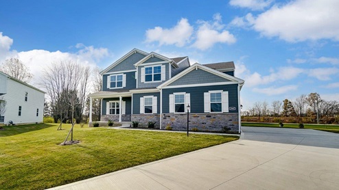 two story home with blue siding, stone water table, covered front porch and sideload garage