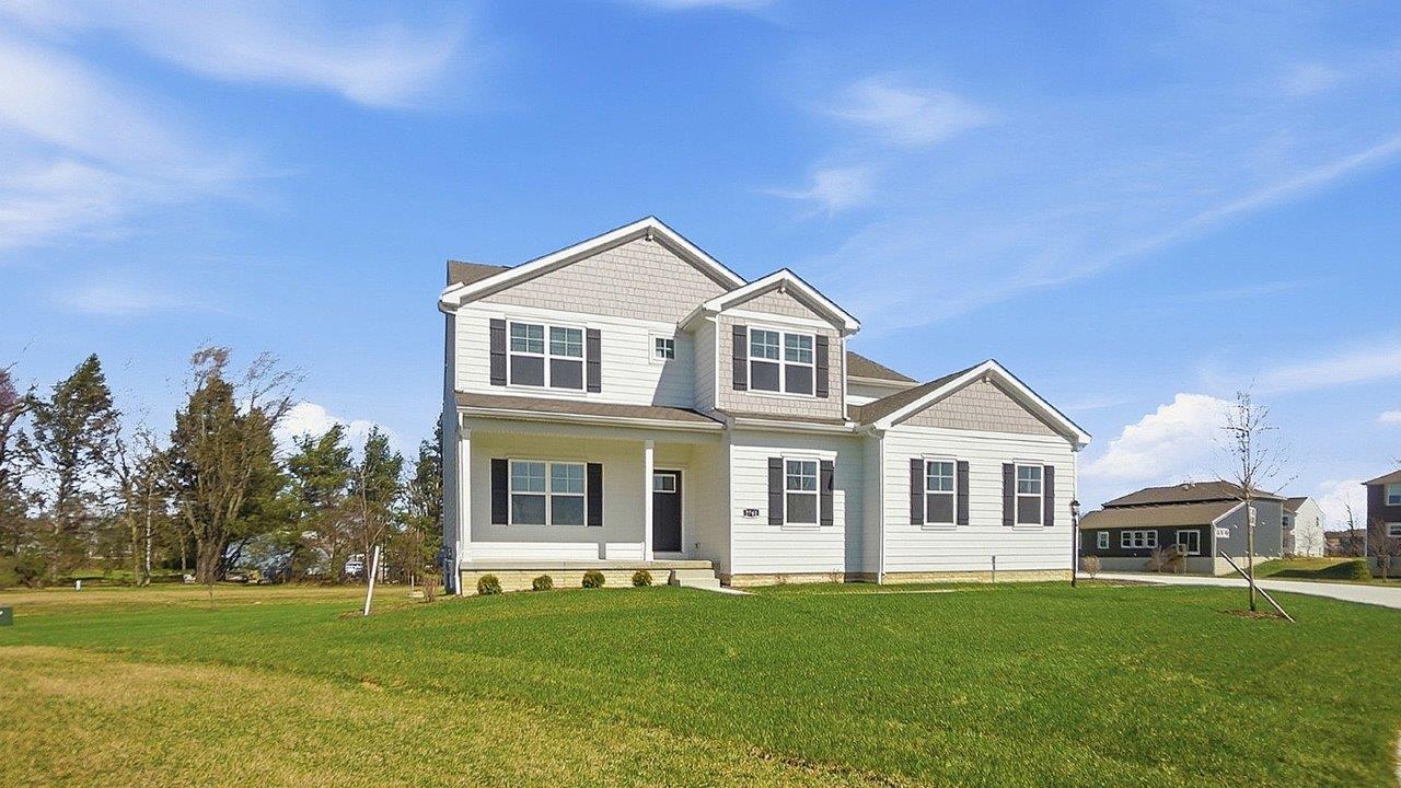 Two story home with white siding, black shutters, covered front porch and sideload garage
