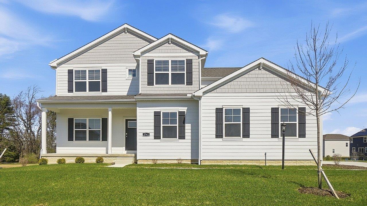 Two story home with white siding, black shutters, covered front porch and sideload garage