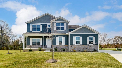 two story home with blue siding, stone water table, covered front porch and sideload garage