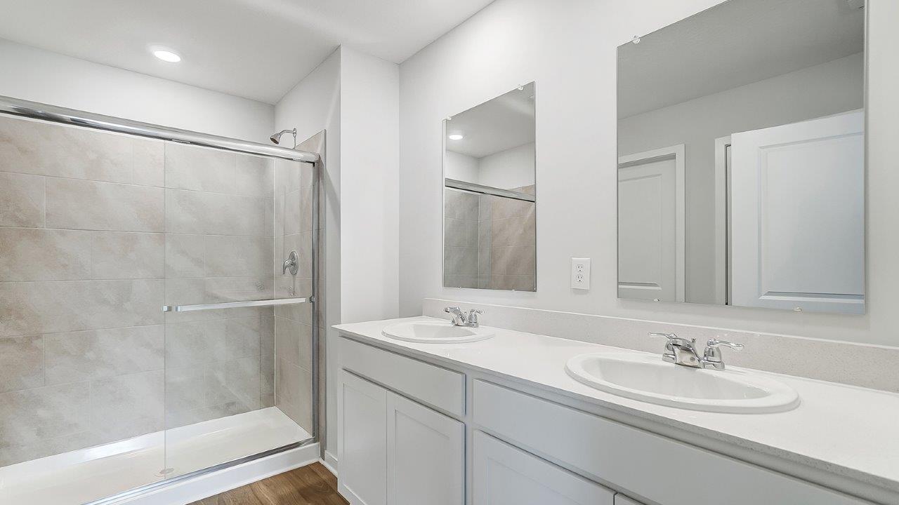 bathroom with dual vanity sinks, toilet and a shower