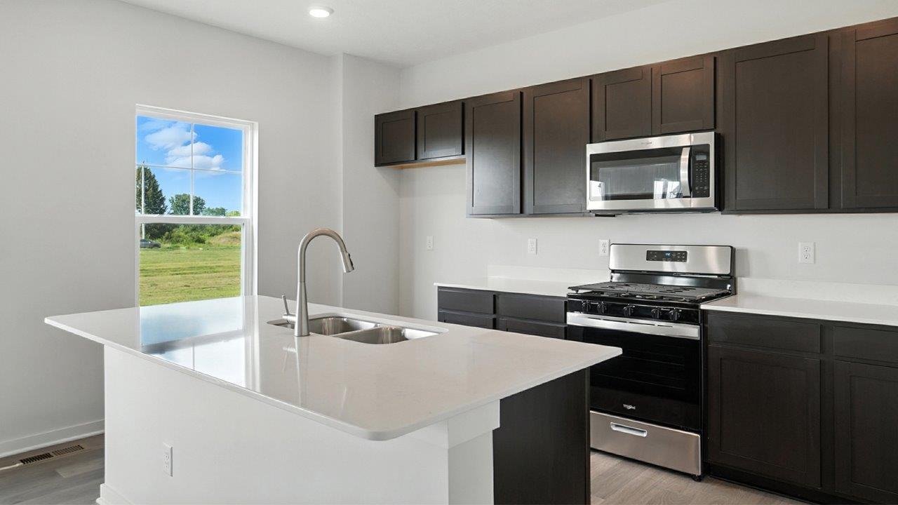 kitchen with brown cabinets, built in island, stainless steel appliances, single window